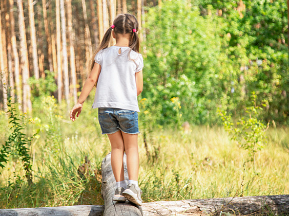 girl balancing on log in nature